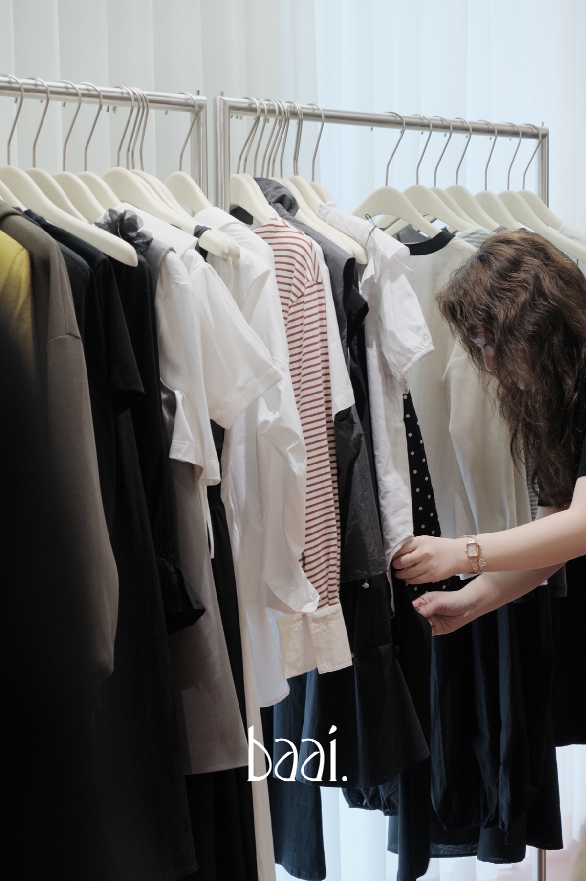 baai店主在试营业期间整理店内衣架上的女装